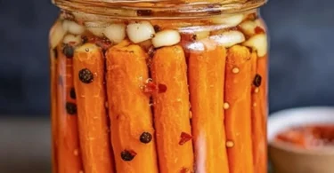 Hot honey pickled carrots in a jar with vibrant colors and spices.
